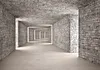 A long, stone-walled corridor with multiple doorways leading into darkness. Produktbild-Vorschau