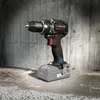 A cordless drill is placed on a concrete surface in front of a concrete wall. Produktbild-Vorschau