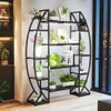 A multi-tiered plant stand with built-in grow lights, filled with various potted plants, placed indoors near a window with a city view at night. Produktbild-Vorschau