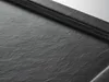 A close-up view of a textured black shower tray. Produktbild-Vorschau