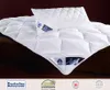 A white quilted comforter and pillow are displayed on a dark brown surface. Produktbild-Vorschau