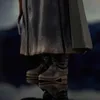 A close-up view of the lower legs and boots of a figure, with a dark, textured cloak draped over them. The boots appear worn and weathered, and the cloak has a similar distressed texture. Náhľad obrázku produktu