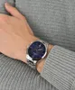 A person's wrist wearing a silver watch with a blue dial. Náhľad obrázku produktu