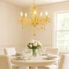 A dining table set with white chairs and a chandelier. Anteprima dell’immagine prodotto