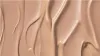 A close-up, abstract texture shot of a light beige liquid, likely foundation or BB cream, with visible swirls and highlights. Anteprima dell’immagine prodotto