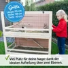 A young girl looking at a two-story rabbit hutch in a garden setting. Produktbild-Vorschau