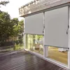 A balcony with wooden decking and a glass railing, featuring two grey roller blinds on a sliding glass door. Náhled obrázku produktu