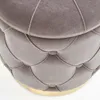 Close-up view of a tufted ottoman with a gold base. Produktbild-Vorschau