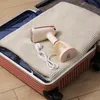 A portable garment steamer is placed on a folded beige knitted blanket inside an open suitcase. Produktbild-Vorschau