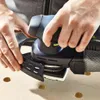 A person is using a Festool Akku-Deltaschleifer DTSC 400 3,0 I-Plus on a wooden surface with holes. Voir les images du produit