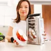 A woman is holding an apple and a grater in a kitchen setting. Produktbild-Vorschau