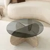 A modern living room setting with a round glass coffee table with a travertine base. Produktbild-Vorschau