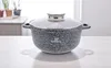 A speckled gray pot with a glass lid sits on a light-colored wooden table, with blurred plants and furniture in the background. Produktbild-Vorschau