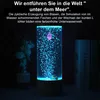 A decorative lava lamp with a pink jellyfish and colorful fish at the bottom, surrounded by blue bubbles and illuminated by blue light. Produktbild-Vorschau