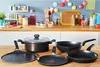 A collection of cookware, including pots and pans, arranged on a wooden countertop in a kitchen setting. Anteprima dell’immagine prodotto