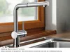 A kitchen faucet is shown in front of a window with wooden trim, above a sink. Náhled obrázku produktu