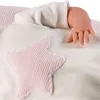 A close-up of a baby doll's arm and hand emerging from a white blanket with a pink star applique. Podgląd zdjęcia produktu