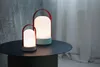 Two LED lanterns with red handles and light blue bases sit on a dark round table. Produktbild-Vorschau