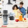 A couple is in a kitchen, and a blender with two cups and some apples and juice are on a wooden counter. Podgląd zdjęcia produktu