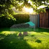 Two rabbits in a wire enclosure with a green roof, set up on a grassy lawn in a backyard during sunset. Náhled obrázku produktu