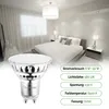 A bedroom with a bed, curtains, and a lamp, with a close-up of an LED bulb in the foreground. Produktbild-Vorschau