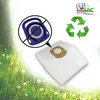 A vacuum cleaner bag is shown in the foreground with a no symbol over a vacuum cleaner part in the upper left, and a recycling symbol made of grass in the upper right. The background is a blurry image of a green meadow with trees. Náhled obrázku produktu