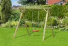 A wooden swing set with a red swing seat is set up on a green lawn in a garden setting. Produktbild-Vorschau