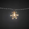 A single snowflake-shaped LED light on a string of lights against a dark background. Produktbild-Vorschau