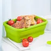A green silicone food container filled with food and tomatoes, placed on a white cloth. Náhled obrázku produktu