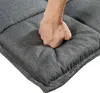 A hand is pressing into a dark gray upholstered cushion, demonstrating its softness and padding. Voir les images du produit