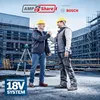 Two construction workers shaking hands on a construction site with buildings and scaffolding in the background. Produktbild-Vorschau