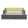 A dark gray sofa bed with its mattress frame extended, showing the wooden slats and a yellow LED light strip at the headboard. Produktbild-Vorschau