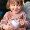A baby is holding a baby bottle. Produktbild-Vorschau