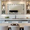 A modern dining room with a table and chairs in the foreground, and a kitchen island with a mirror and sink in the background. Náhled obrázku produktu