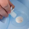 A hand is holding a white plastic threaded cap over a blue plastic opening. Produktbild-Vorschau