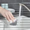 A hand is scrubbing a metal rack with a sponge under running water. Anteprima dell’immagine prodotto