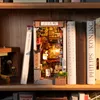 A 3D wooden book nook model of a Japanese alleyway is displayed on a wooden shelf between books. Voir les images du produit
