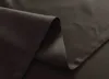 A close-up view of dark brown fabric, folded to show texture and stitching. Produktbild-Vorschau