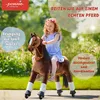 A young girl riding a toy horse in an outdoor setting. Produktbild-Vorschau