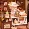 A miniature bakery display with a doll and various pastries. Anteprima dell’immagine prodotto