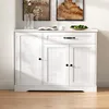 A white sideboard with a drawer and three doors, placed on a wooden floor against a white wall. Decorative items are on top. Anteprima dell’immagine prodotto