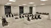 A showroom or display area filled with various commercial kitchen appliances, primarily waffle makers and similar equipment, arranged on white display stands. Podgląd zdjęcia produktu