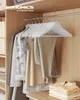A closet interior with clothes hanging on white wooden hangers. Produktbild-Vorschau