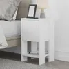 A white nightstand next to a bed, with a lamp and e-reader on top. Produktbild-Vorschau