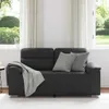 A black sofa with two gray cushions and a gray blanket draped over the armrest, placed in a room with large windows showing a garden view. Voir les images du produit