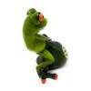 A small, green, ceramic frog figurine holding a green money bag with a gold symbol on it, set against a white background. Produktbild-Vorschau