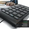 A person's hand is using a black numeric keypad connected to a computer. Voir les images du produit