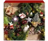 A festive arrangement of Christmas decorations, including ornaments, a small tree, and gift boxes, intertwined with a fir garland and fairy lights, set against a rustic wooden background. Produktbild-Vorschau