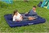 A couple relaxing on an inflatable mattress in a grassy outdoor setting with tents in the background. Anteprima dell’immagine prodotto