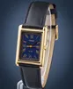 A close-up studio shot of a gold-toned rectangular watch with a blue face and a black leather strap. Produktbild-Vorschau